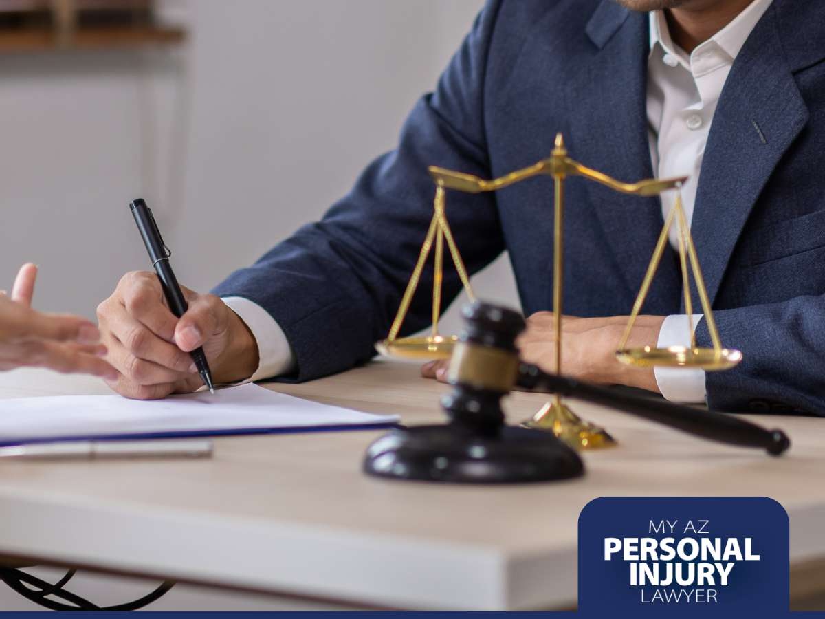 Injury attorney discussing a case with a client, with a gavel and scales of justice on the table